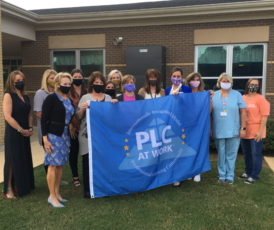 faculty and staff holding the Model PLC flag faculty and staff holding the Model PLC flag